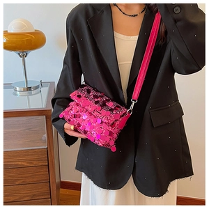 Detail of a sparkling pink sequin crossbody bag with metal chain on a black blazer