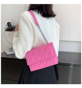Detail of rose pink rectangular shoulder bag with geometric quilted pattern and chain strap