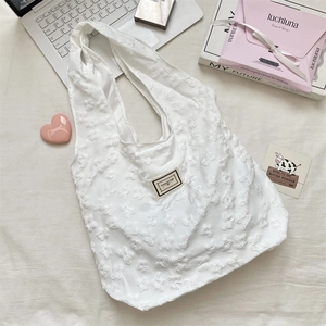 Detailed view of the 3D floral jacquard fabric on the white shoulder tote bag