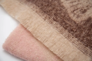 Detail of soft jacquard ginkgo leaf scarves with fringe edges in brown and pink
