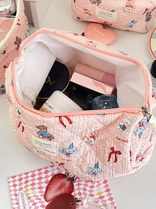Top view of pink quilted cartoon makeup bag showing spacious interior with skincare items