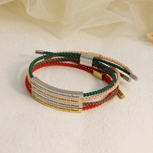 Macro shot of colorful woven bracelets with engraved inspirational metal plaques