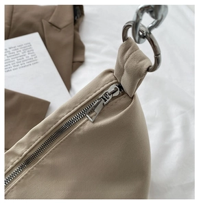 Detailed close-up of a smooth silver metal zipper and chain strap on a khaki canvas bag