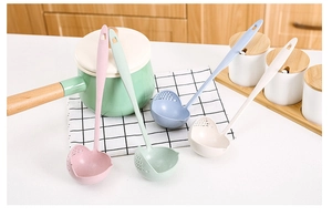 Close-up of four wheat straw soup spoons with drainage holes in pastel colors on a counter