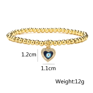 Detail of evil eye heart pendant with dimensions 1.2x1.1cm on gold beaded bracelet