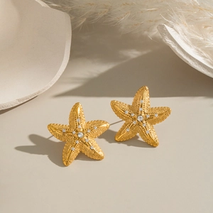 Elegant gold starfish earrings with sparkling zircon stones on a minimalist background