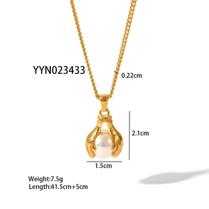 Detailed view of gold necklace featuring two hands holding a pearl pendant with size specs
