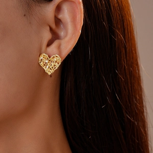 Close-up of golden mesh heart earring with zircon stones worn by a model