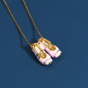 Detailed close-up of pink ballet slipper pendant with gold trim on a navy background