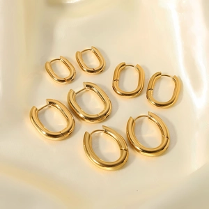Polished gold stainless steel oval hoop earrings in three sizes on silk background