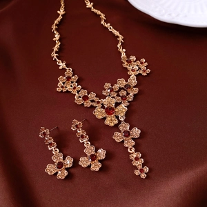Exquisite gold-tone necklace and earring set with red gemstones on brown silk fabric