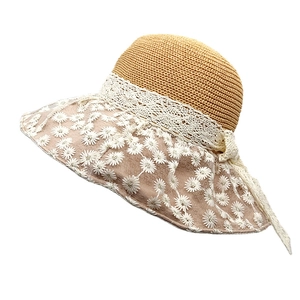 Detailed close-up of straw woven hat with lace bow and daisy embroidered mesh brim