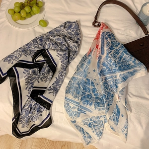 Detail of paisley and city map print silk scarves next to a stylish leather bag