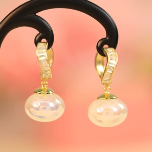 Macro shot of gold earring with cubic zirconia studs and an iridescent aurora bead detail