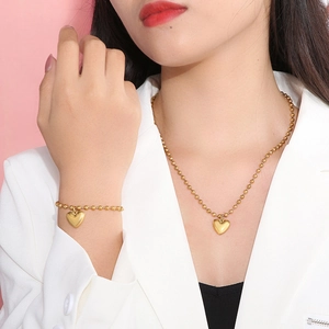 Gros plan d'un ensemble collier et bracelet cœur perlé plaqué or 18 carats sur un modèle