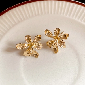 Detailed macro shot of 3D blooming golden flower earrings with metallic petal texture