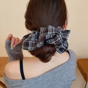 Close-up of black and white plaid scrunchie worn on a low bun hair style
