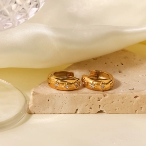 Detail of 18k gold plated star evil eye hoop earrings with cubic zirconia on stone