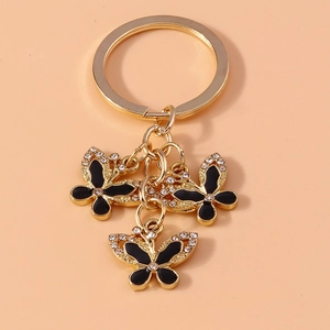 Detail of gold metal keychain with three black butterfly pendants and sparkling rhinestones