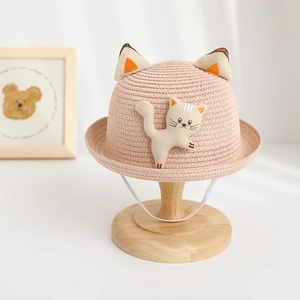 Close-up of pink straw sun hat for toddlers with cute cat ears and embroidery details