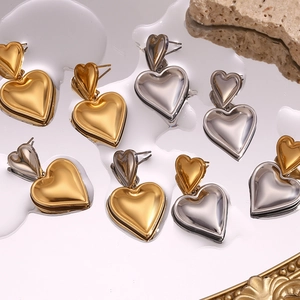 Macro shot of gold and silver double heart earrings with water drops on mirror surface