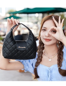 Detail of black quilted PU handbag featuring gold metal clasp and top handle texture