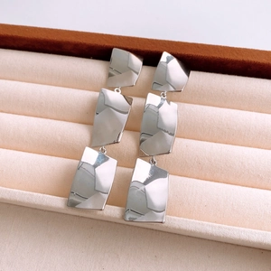 Macro shot of silver tiered square tassel earrings with polished mirror finish on velvet