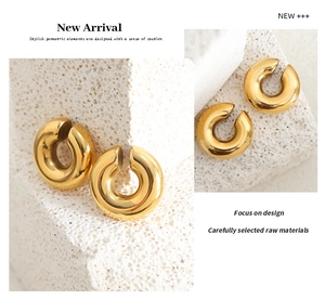 Macro shot of thick C-shaped gold plated titanium steel hoop earrings with mirror finish