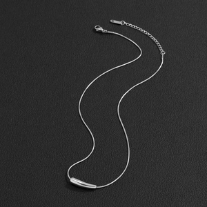 Minimalist silver snake chain necklace with a sleek bar pendant on a dark surface