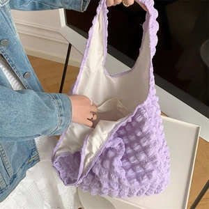 Detail shot of purple bubble texture tote bag with spacious interior held by a model