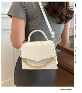Detail of white crocodile texture crossbody bag with gold chain and top handle