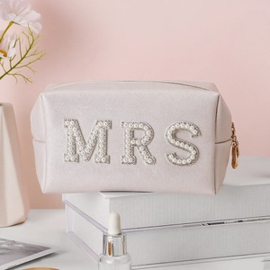 Macro detail of pearl and rhinestone MRS lettering on a pink leather makeup bag