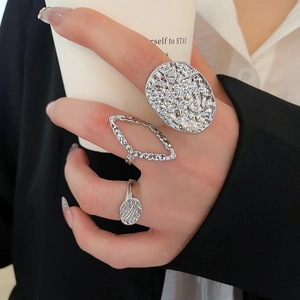 Close-up of three silver textured rings worn with a black suit and white coffee cup