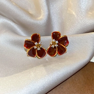 Macro shot of 18K gold plated vintage burgundy enamel flower earrings with zircons