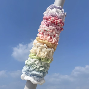 Outdoor display of various floral and solid color scrunchies against a clear blue sky