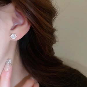 Close-up of sparkling zircon snowflake earrings worn on model for a refined look