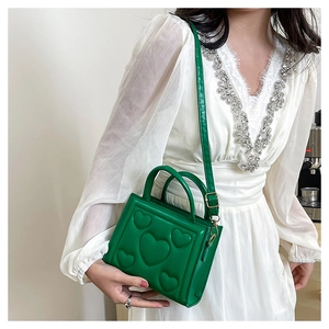 Détail du sac à main carré vert avec motif cœurs en relief et garnitures dorées