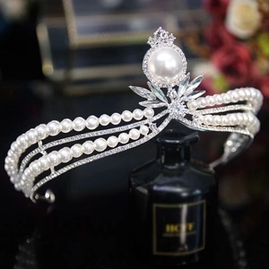 Macro shot of silver bridal crown with white pearls and sparkling crystals on black bottle