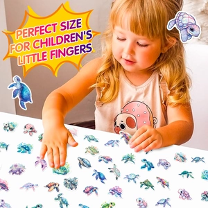 Toddler playing with colorful sea turtle stickers on a white table for DIY crafts