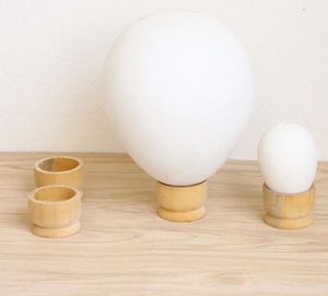 Minimalist white egg-shaped lamps with natural wooden bases on a light surface