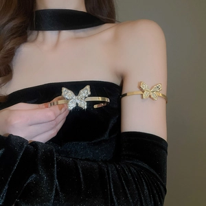 Close-up of sparkling crystal butterfly arm cuff in gold finish worn by model