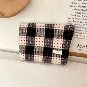 Close-up of black and white plaid tweed makeup bag with red dots and brand logo label