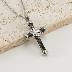 Vue macro d'un pendentif croix en acier inoxydable avec bords torsadés et trèfle