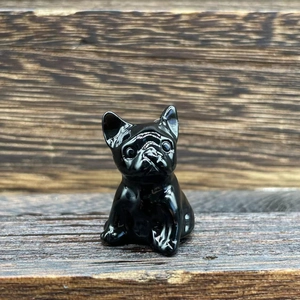 Detailed view of a small black french bulldog figurine on a natural wood surface