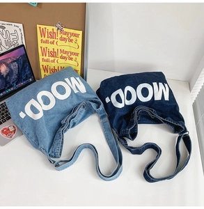Detail of light and dark denim crossbody bags with white MOOD. lettering in a campus setting