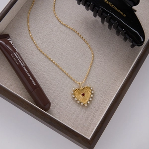 Golden heart necklace with red gem and diamonds in a jewelry box setting