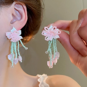 Detail of handmade beaded flower earrings with mint green fringe and pink accents