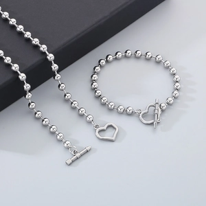 Detail of silver beaded necklace and bracelet set with unique heart-shaped toggle clasp