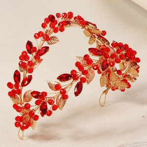 Detail of a gold bridal headband with sparkling red rhinestones and metallic leaf design