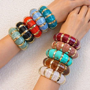 Close-up of colorful acrylic geometric bracelets with marbled texture and gold metal rings